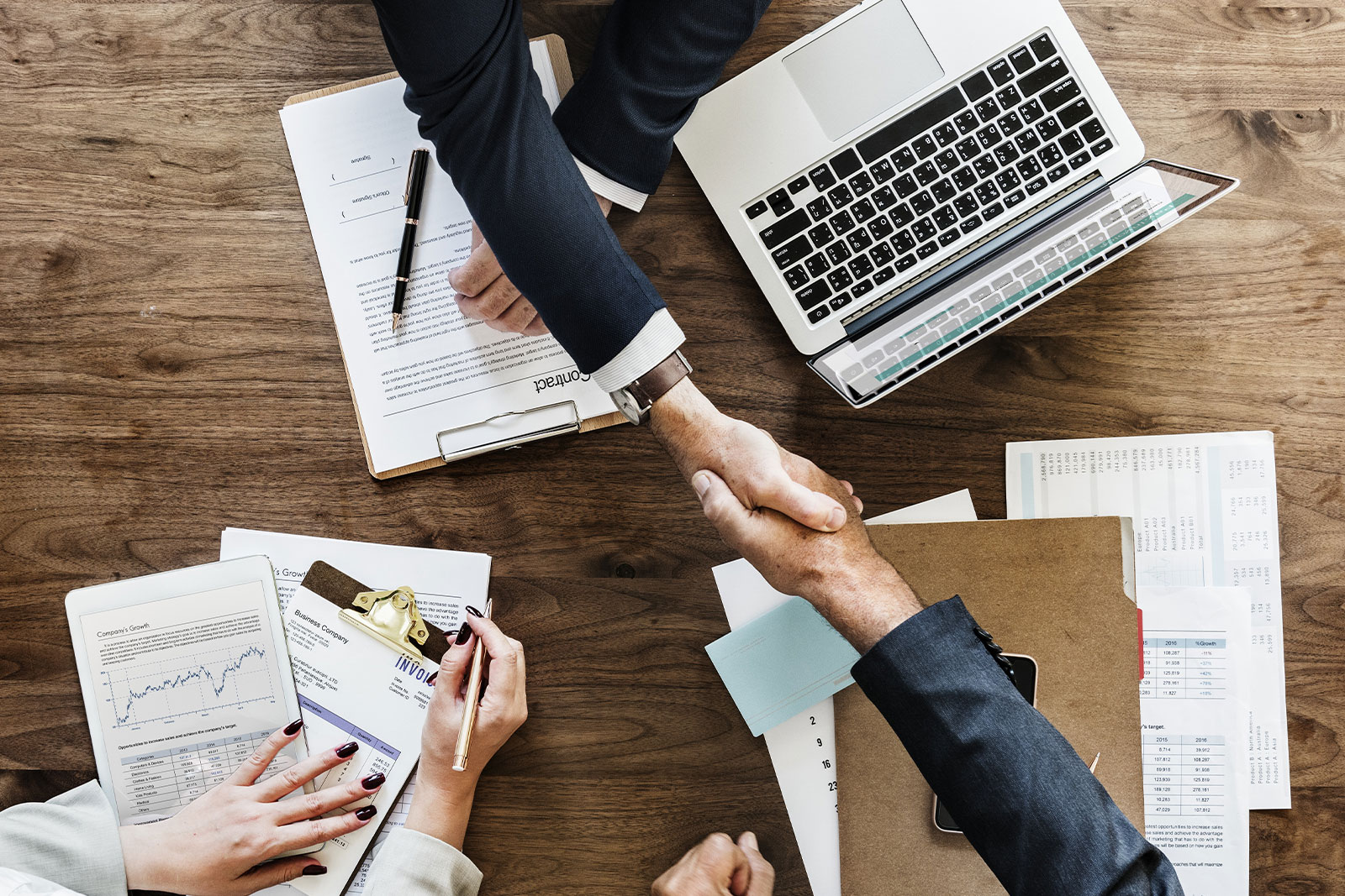 Image of hand shake over paper work