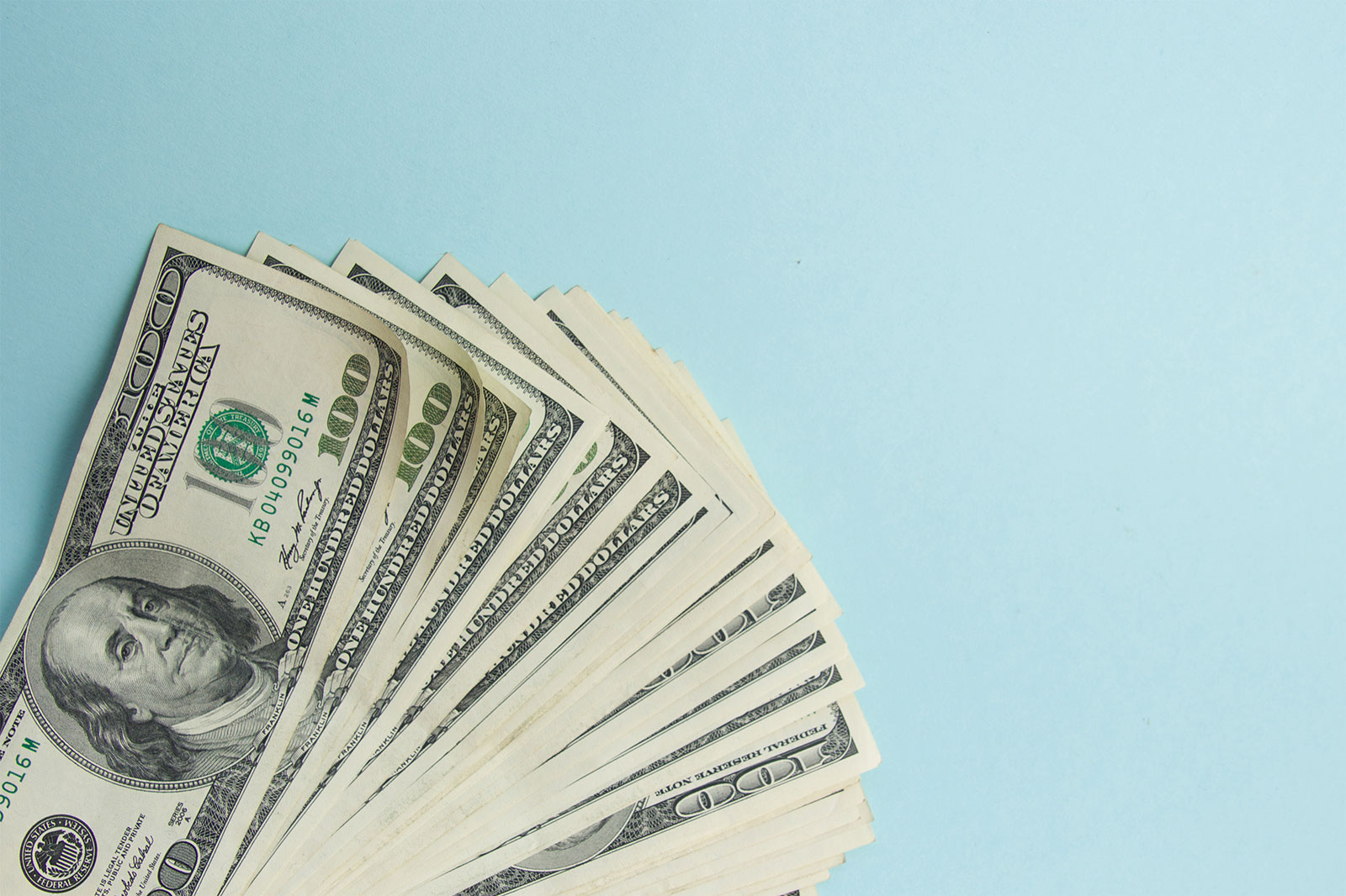 Image of a stack of money on a light blue backdrop 